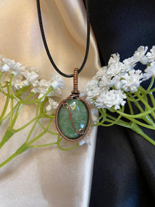 dark green oval nephrite jade pendant with silver shimmer flash wrapped in oxidized copper wire with looped wire detailing. Comes on a 20" black adjustable cord. Made with love.